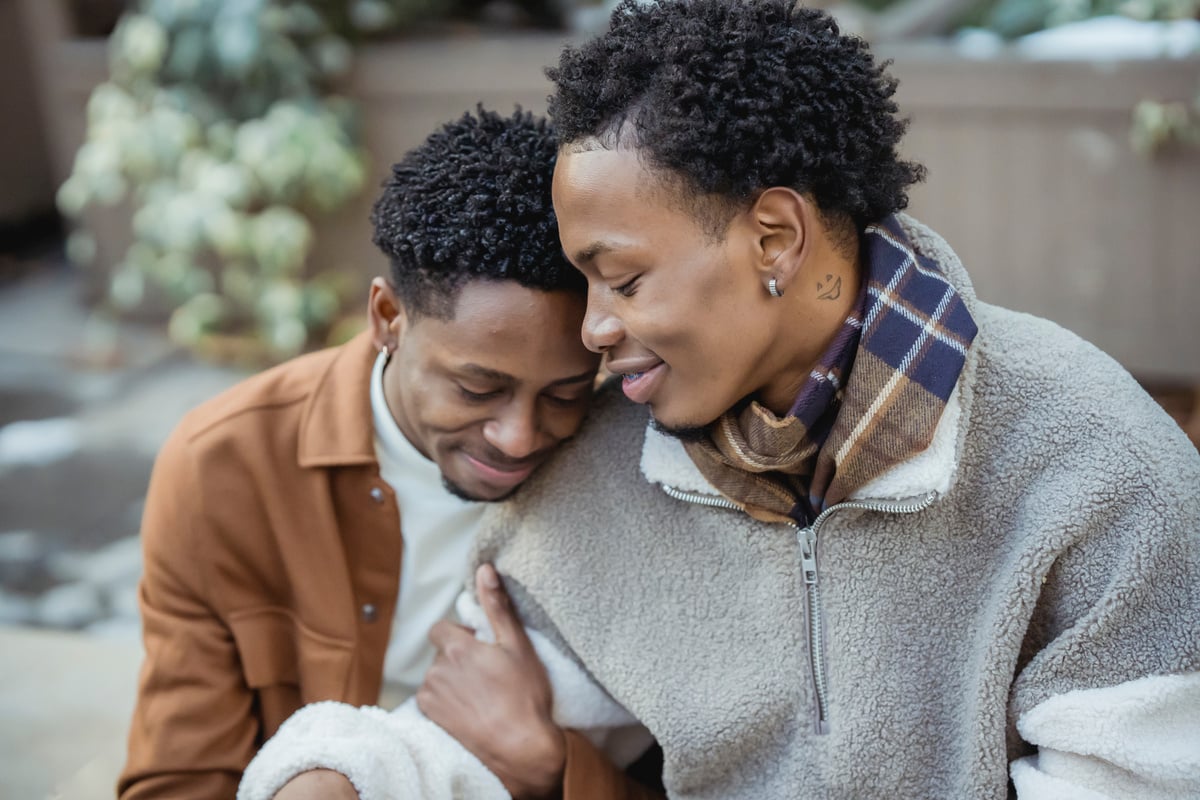 Loving black homosexual couple hugging on street